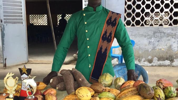 Le jeune Mambo Sika présentant des produits agricoles locaux dans un stand.