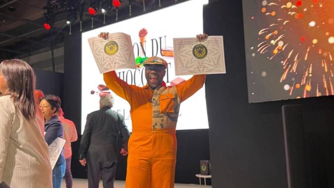 Axel Emmanuel brandissant fièrement ses deux distinctions.